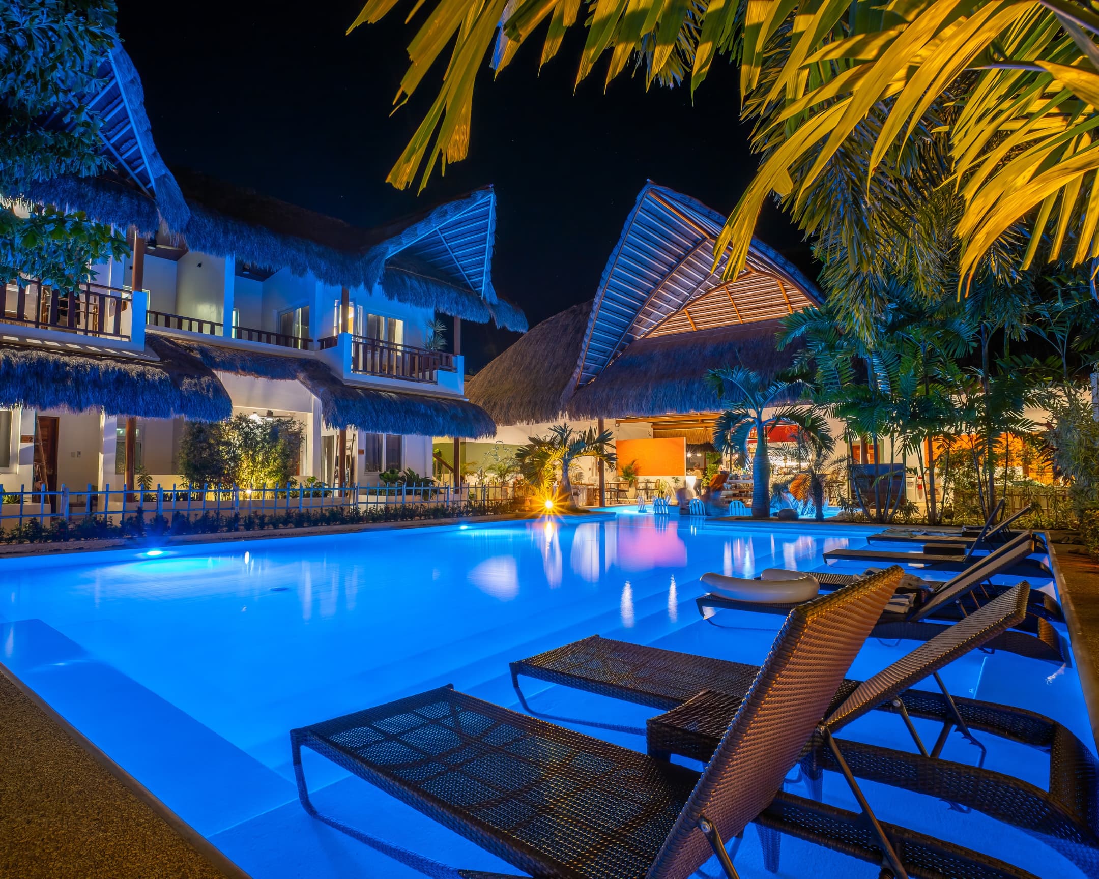 Pool loungers beside the illuminated pool at Bathala Resort