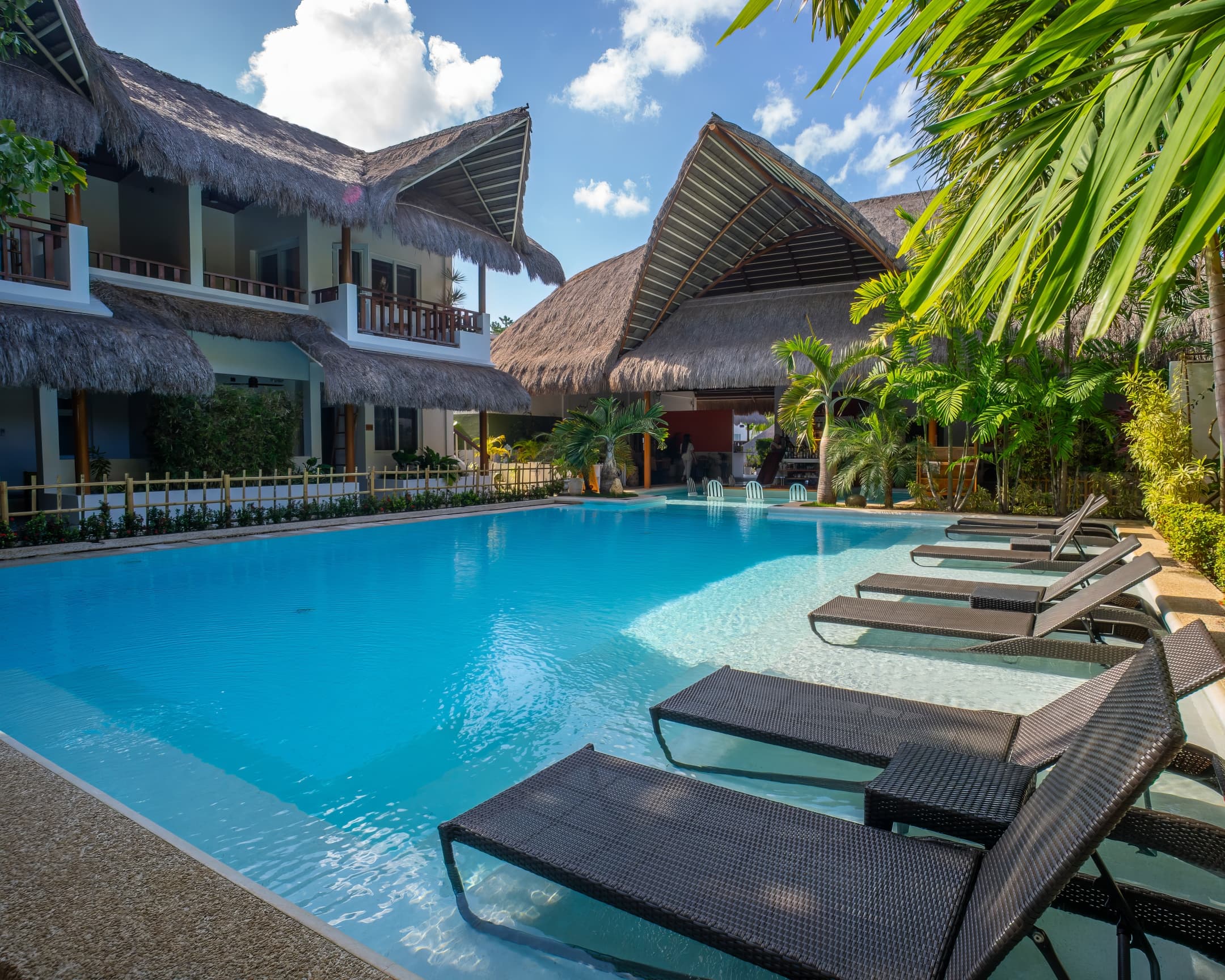 Daytime pool with loungers and palm shade at Bathala Resort