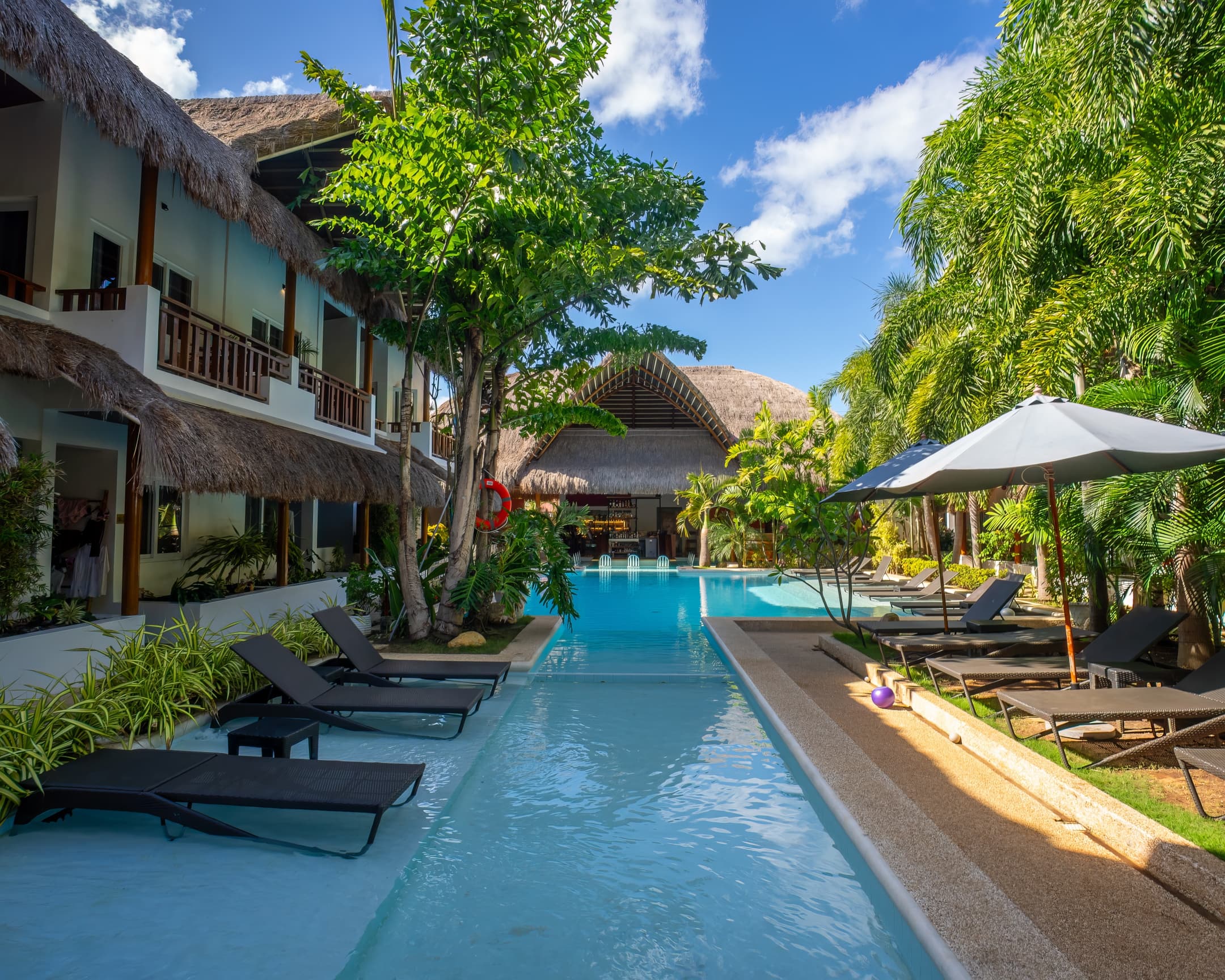 Shaded pool edge beside garden and guest balconies at Bathala Resort